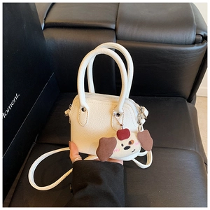 Close-up of white mini girl handbag with cute dog plush pendant and litchi texture