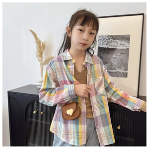 Détail d'un sac bandoulière en cuir marron avec boucle coeur sur chemise fille
