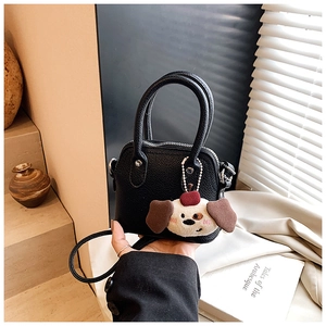 Close-up of black mini bag with litchi texture and cute plush dog charm