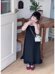 Detail of a black strapless girl's long dress with elegant ruffle hem and cotton fabric