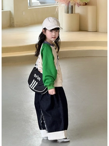 Detail of children's black crossbody bag with white stripe design and orin lettering