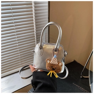 Detail of silver metallic mini bag with cute plush bear charm and crossbody strap