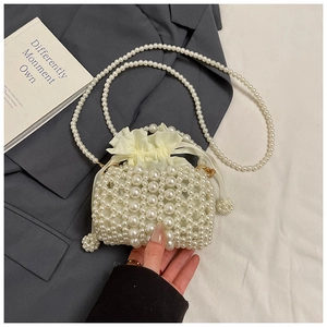 Detail of white pearl woven mini bag featuring silk drawstring pouch and long chain strap