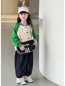 Detail of a child wearing a green striped baseball jacket and casual crossbody bag
