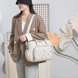 Quilted beige diaper bag with polka dot pattern and functional multi-pocket design