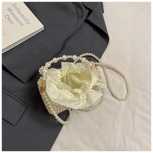 Detail of white pearl woven drawstring bag with crossbody strap and fabric lining