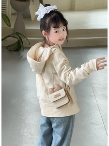 Detail view of a woven straw bow crossbody bag on a beige hooded cardigan sweater