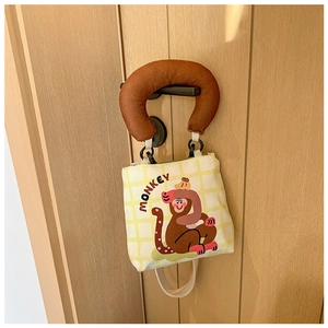 Detail der Canvas-Tasche mit Affen-Print, weichen braunen Griffen und gelbem Karo