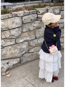 Detail of child's straw crossbody bag with pink bow and elegant metal chain strap