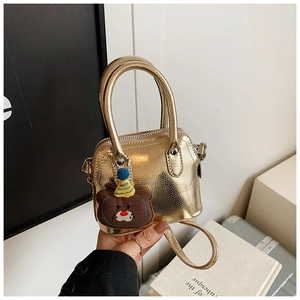 Macro view of metallic gold mini bag with fine grain texture and cute bear pendant