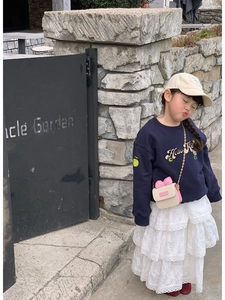 Toddler girl wearing navy sweatshirt with white lace skirt and pink mini crossbody bag