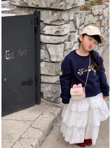 Detail of a straw crossbody bag with a pink bow and gold chain on a child model