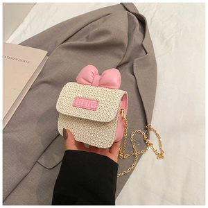 Close-up of mini straw bag with pink bow, orin leather label and gold chain strap