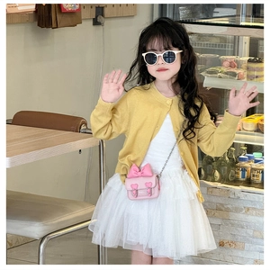 Détail du mini sac bandoulière à nœud rose avec gilet en maille jaune et robe en tulle
