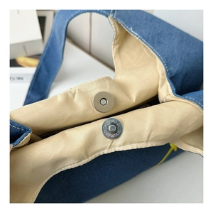 Detailed close-up of the magnetic button closure on a navy denim kids shoulder bag