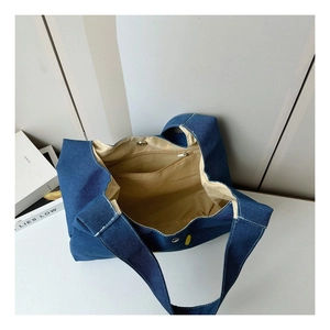 Detail view of denim tote bag interior showing the zipper pocket and magnetic buckle