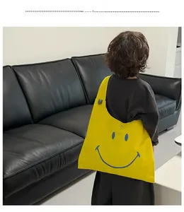 Detailed view of child wearing the large yellow canvas crossbody bag with blue smiley face