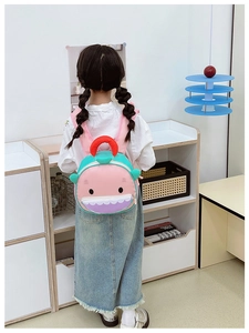 Detail view of pink shark cartoon backpack with zip pocket on a child toddler model