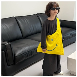 Macro shot of bright yellow canvas kid bag with a large blue smiley face graphic