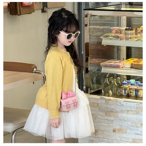 Fillette en cardigan jaune et jupe tutu blanche avec petit sac rose à nœud et chaîne