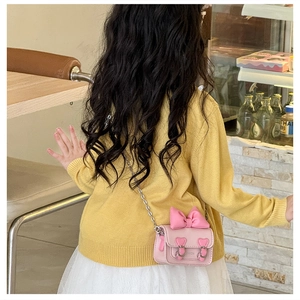 Détail du sac à bandoulière rose pour filles avec nœud, boucles cœur et chaîne