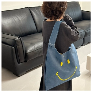 Blue denim kids tote bag with yellow smiley face design worn by a child from behind
