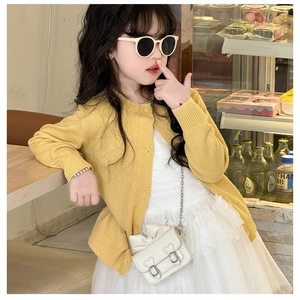 Détail de la texture d'un cardigan en tricot jaune vif avec poignets et bords côtelés
