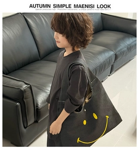 Detailed view of large black canvas kids tote bag featuring a bright yellow smiley face