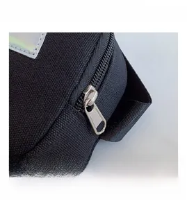 Detail shot of smooth metal zipper and laser brand patch on a nylon kids crossbody bag