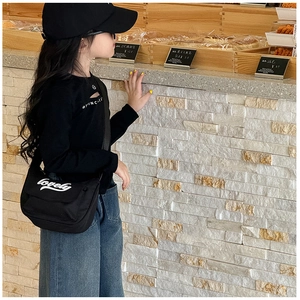 Close-up of black crossbody bag for kids featuring a lovely letter print and flap design