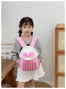Close-up of pink bow and striped pocket on cute toddler backpack worn by a child