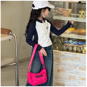 Detailed shot of a bright pink crossbody bag with lovely text on a child outfit