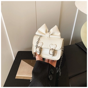 Détail d'un mini sac blanc pour fille avec nœud papillon et bandoulière en chaîne