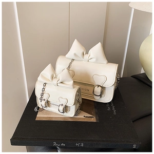 Détail de deux sacs à bandoulière crème pour enfants avec nœuds et boucles en cœur
