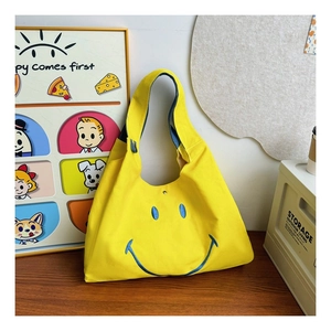 Close-up of yellow canvas tote bag with blue embroidered smiley face and metal snap button