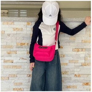 Street style view of a rose red canvas crossbody bag for kids with lovely lettering