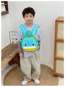 Detail view of a cute blue shark backpack for kids with a yellow zipper pocket