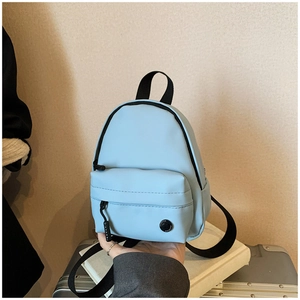 Détail d'un mini sac à dos bleu clair avec poche avant et bandoulière en tissu noir