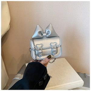 Détail du mini sac argenté avec un grand nœud et des boucles en forme de cœur stylisées