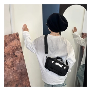 Détail du sac bandoulière cylindrique noir avec imprimé FASHION et boucle sur un enfant