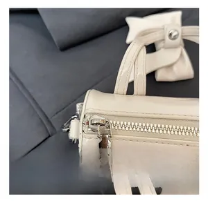 Close-up of the silver metal zipper and bow detail on the cream white kids handbag