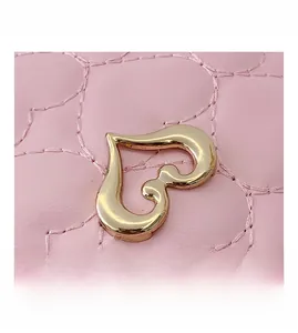 Détail du fermoir doré en forme de cœur sur le sac rose matelassé pour enfants
