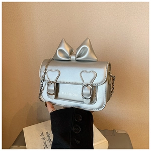 Détail du mini sac à main argenté avec nœud, boucle en cœur et bandoulière chaîne