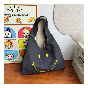 Close-up of a large capacity grey denim kids messenger bag with a yellow smiley face