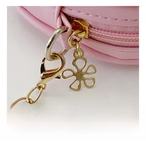 Détail du sac rose pour fille avec fermeture éclair dorée et pendentif fleur en cuir