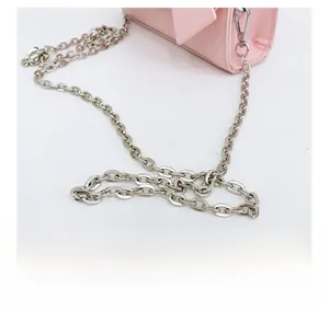 Close-up of silver metal chain strap and light pink glossy leather on a fashion handbag