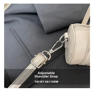 Detail of adjustable shoulder strap with silver metal buckle on a cream cylinder bag