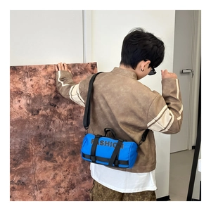 Détail d'un sac bandoulière cylindrique bleu avec lettrage noir FASHION stylé