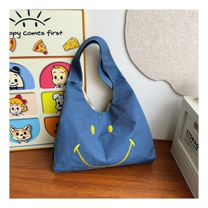 Close-up of blue denim kids tote bag featuring a cute yellow smiley face patch