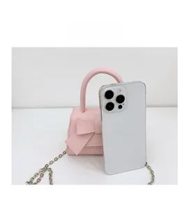 Miniature pink bow handbag shown next to a smartphone for size reference